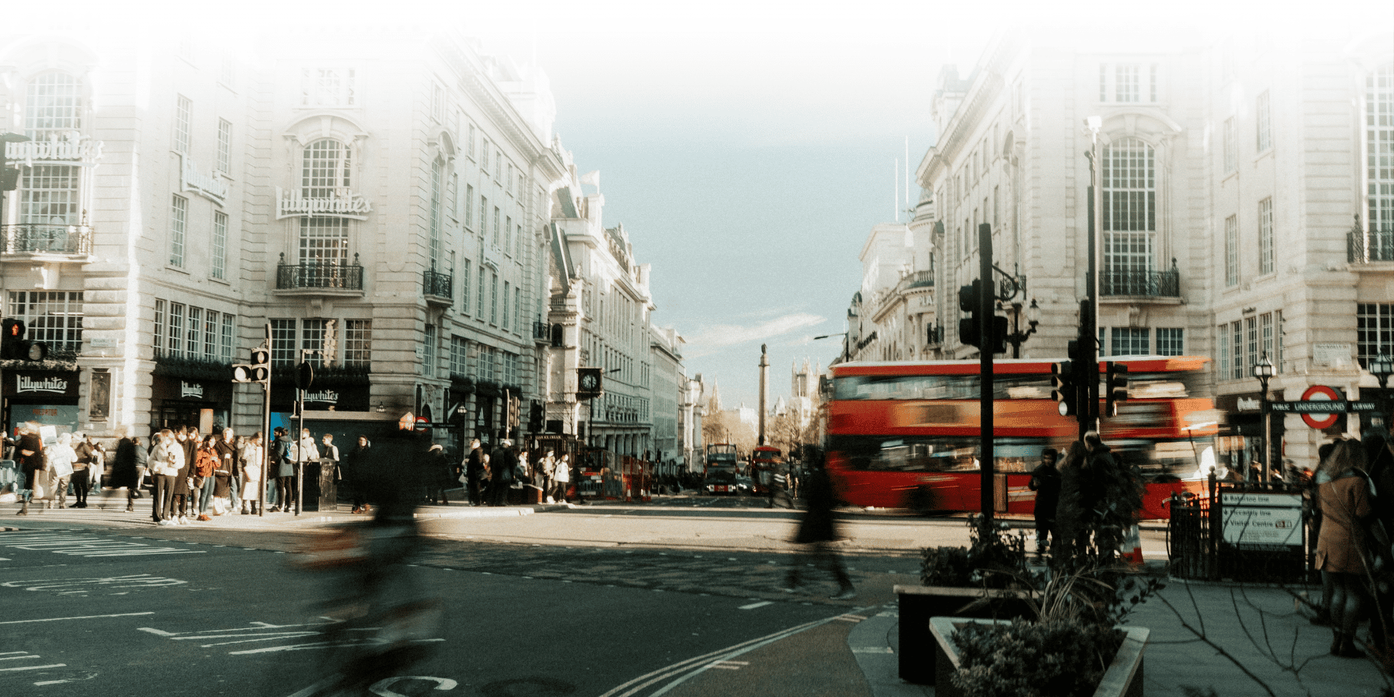 Busy London street scene at Oxford Circus with pedestrians, historic buildings and a red double-decker bus passing through a bustling city centre.