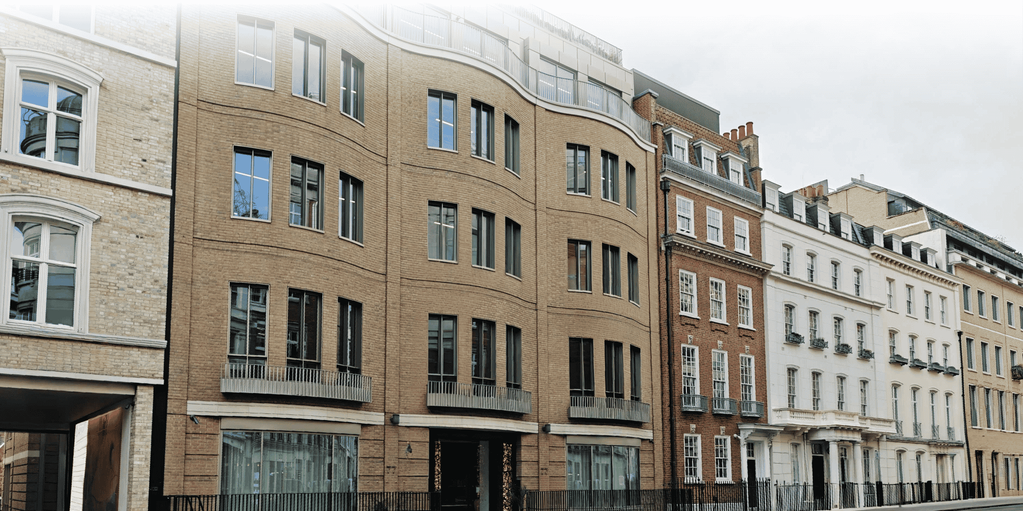 Mixed architectural styles along a London street, with a curved modern brick building beside Georgian townhouses