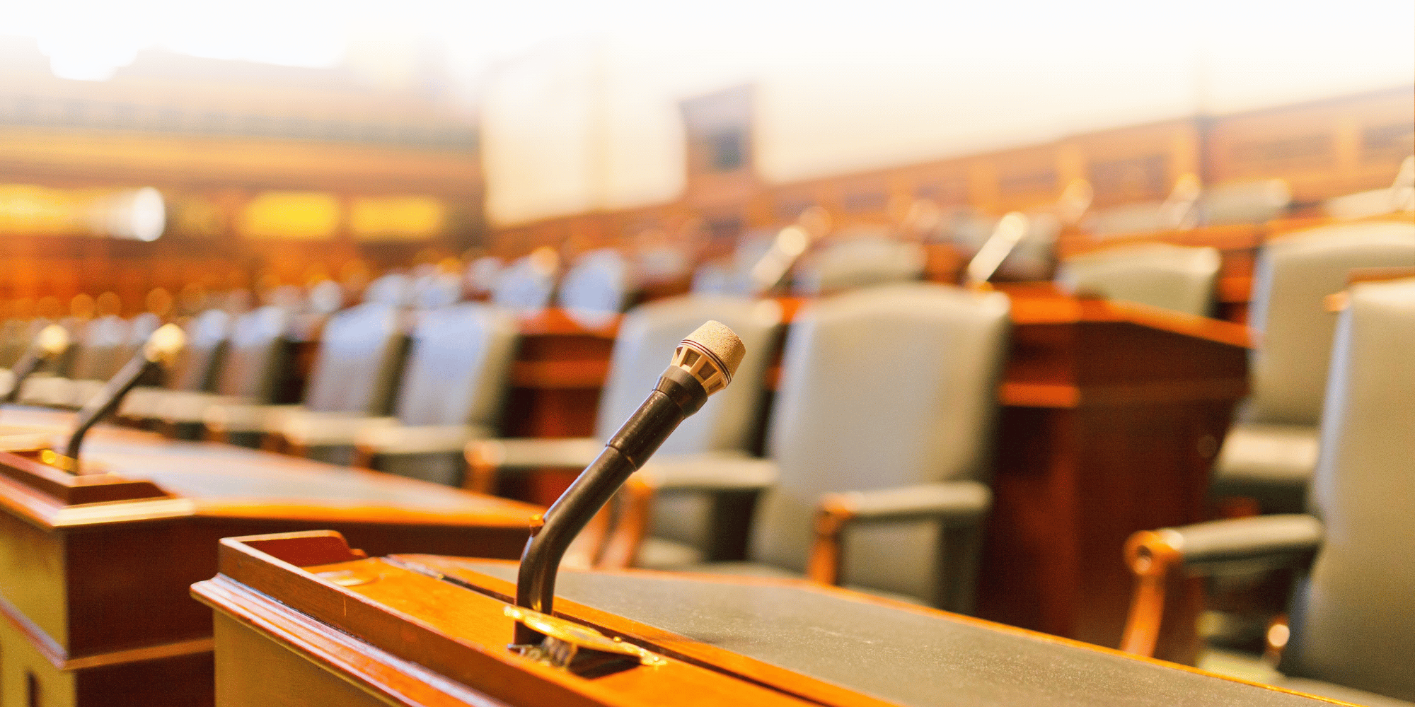 Courtroom microphone with blurred jury seats in the background all with a wooden texture