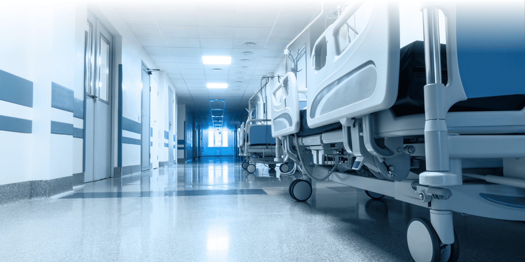 blue light image of a hopsital bed overlooking a corridor