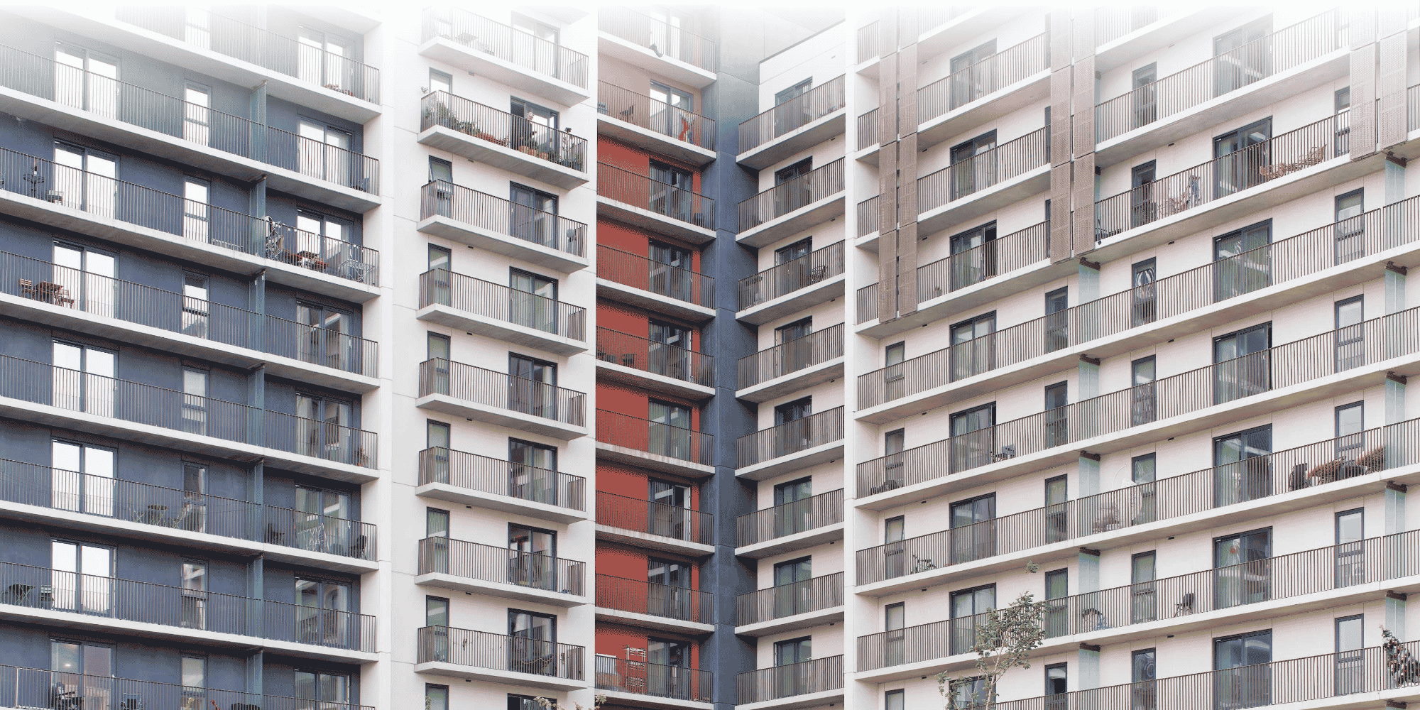Modern high-rise student accommodation with multi-floor balconies and grey, cream, and red panelling.