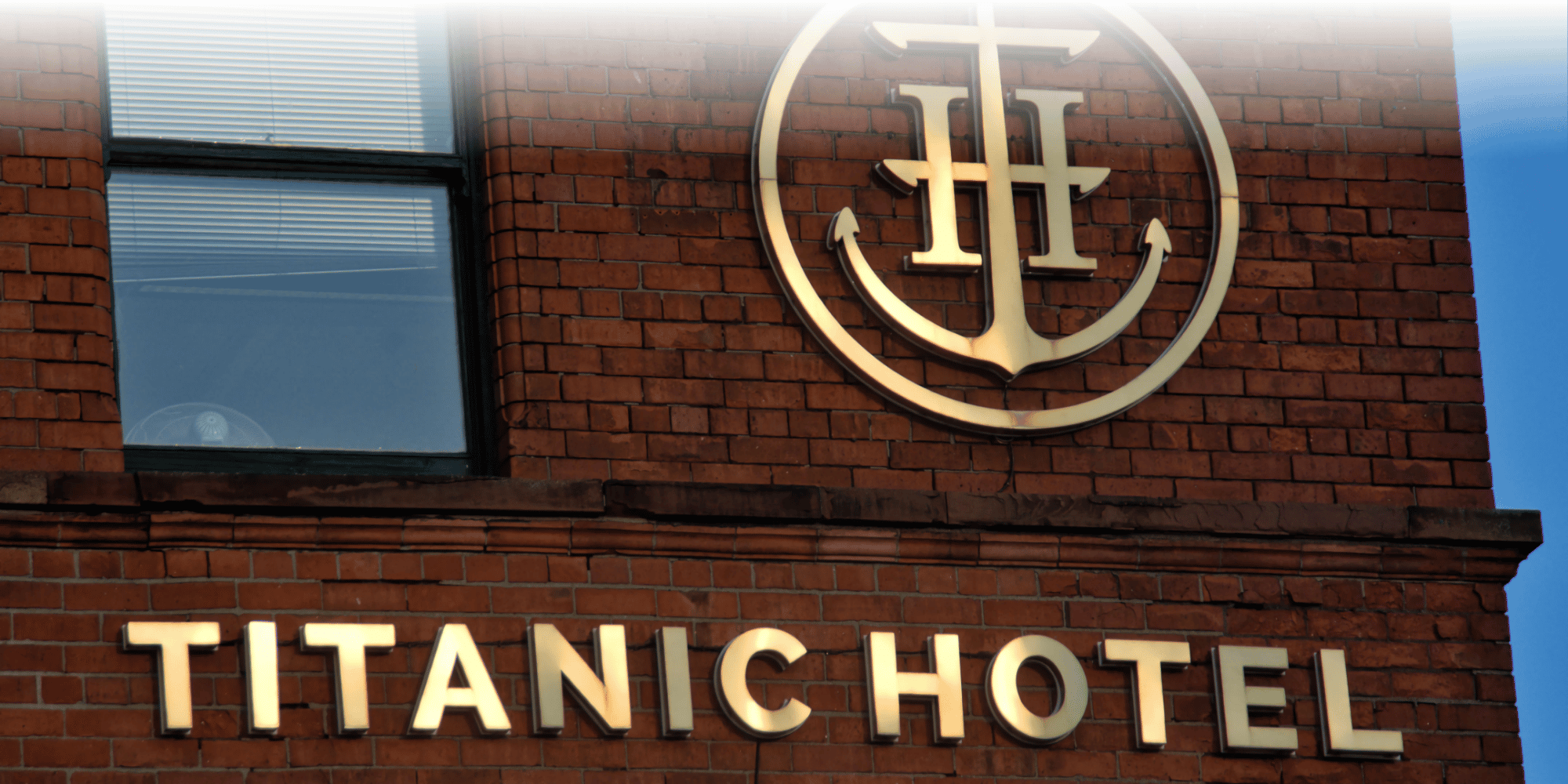 Signage of the Titanic Hotel in gold, layered on a brick wall