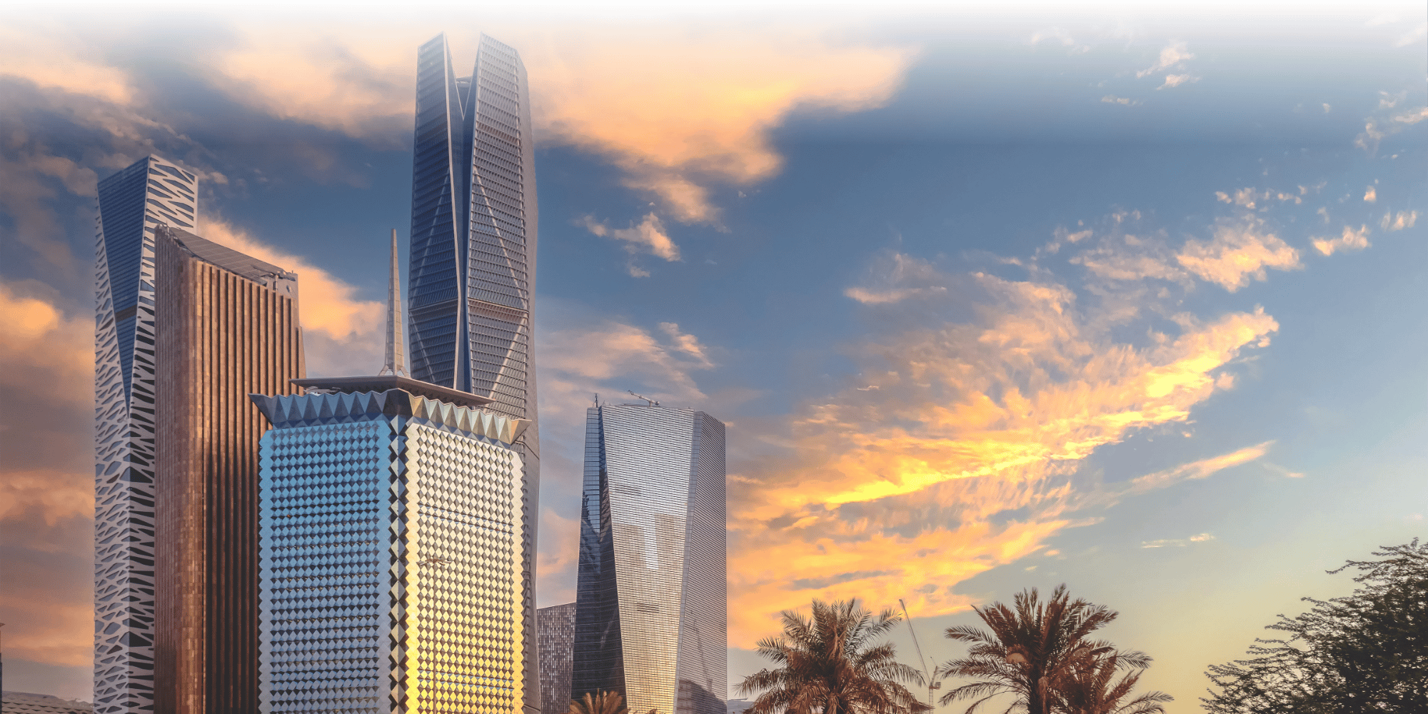 Riyadh's modern skyline at sunset, with striking contemporary skyscrapers and palm trees set against a dramatic golden sky.