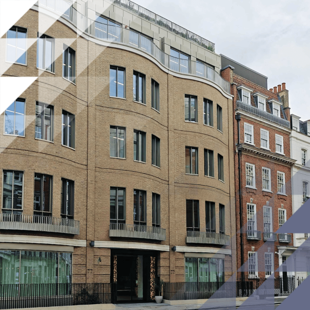 Refurbished brick mixed-use building with ground-floor retail windows and Juliet balconies, among Georgian terraces on a central London street.