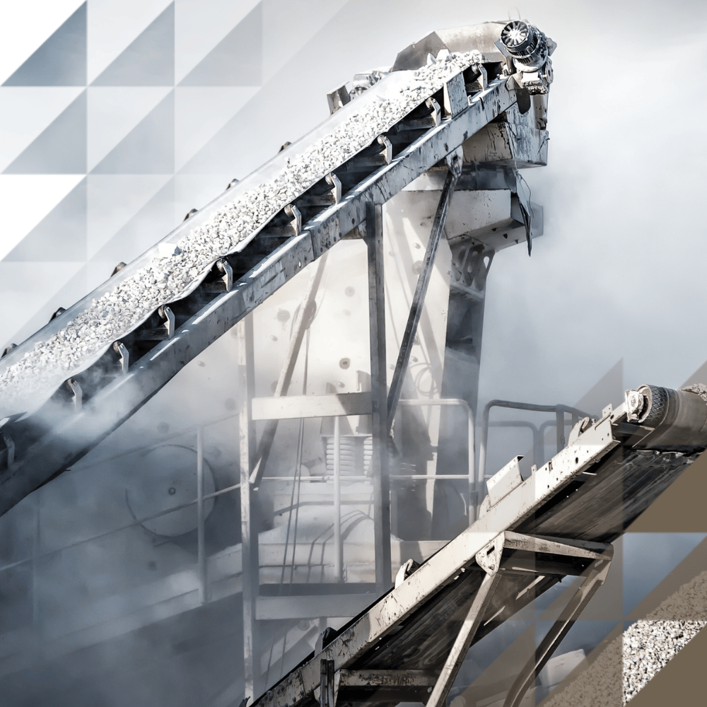 Industrial conveyor belts carrying crushed aggregate at a quarry or processing plant, with dust rising against a dramatic cloudy sky.