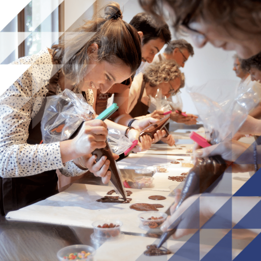Multiple people decorating chocolate eggs with piping bags as part of an experience