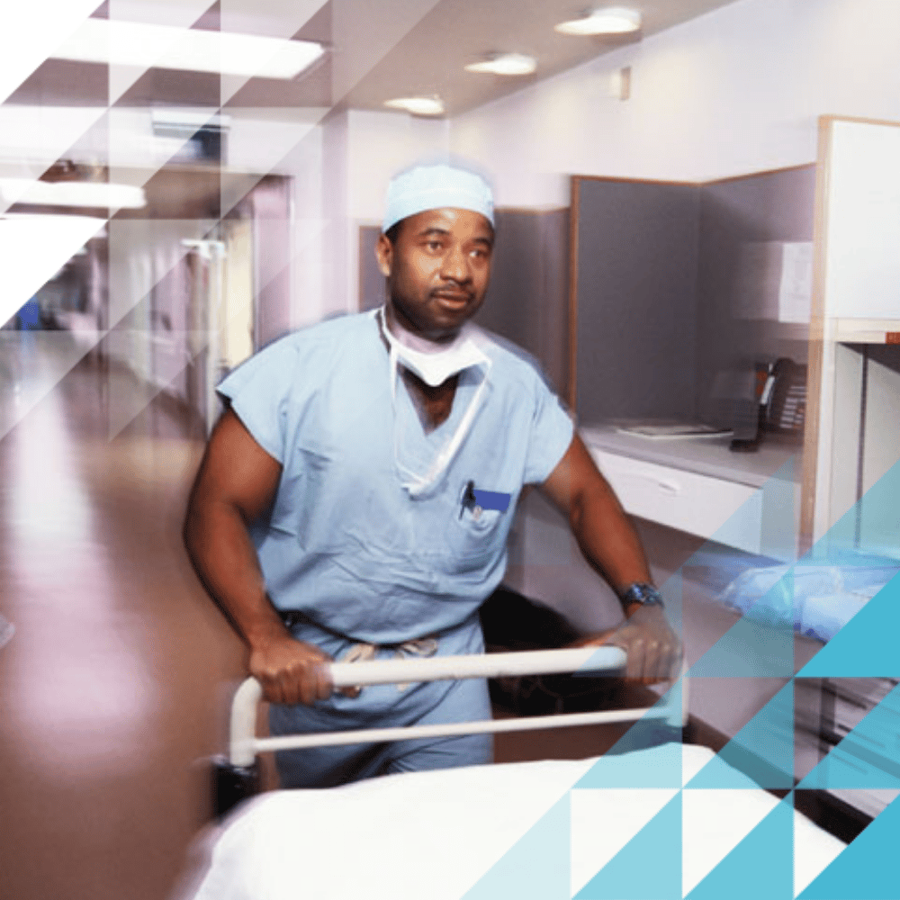 A healthcare worker in blue scrubs and a face mask pushes a hospital bed, with Hochiki branded triangle overlays in the corners.