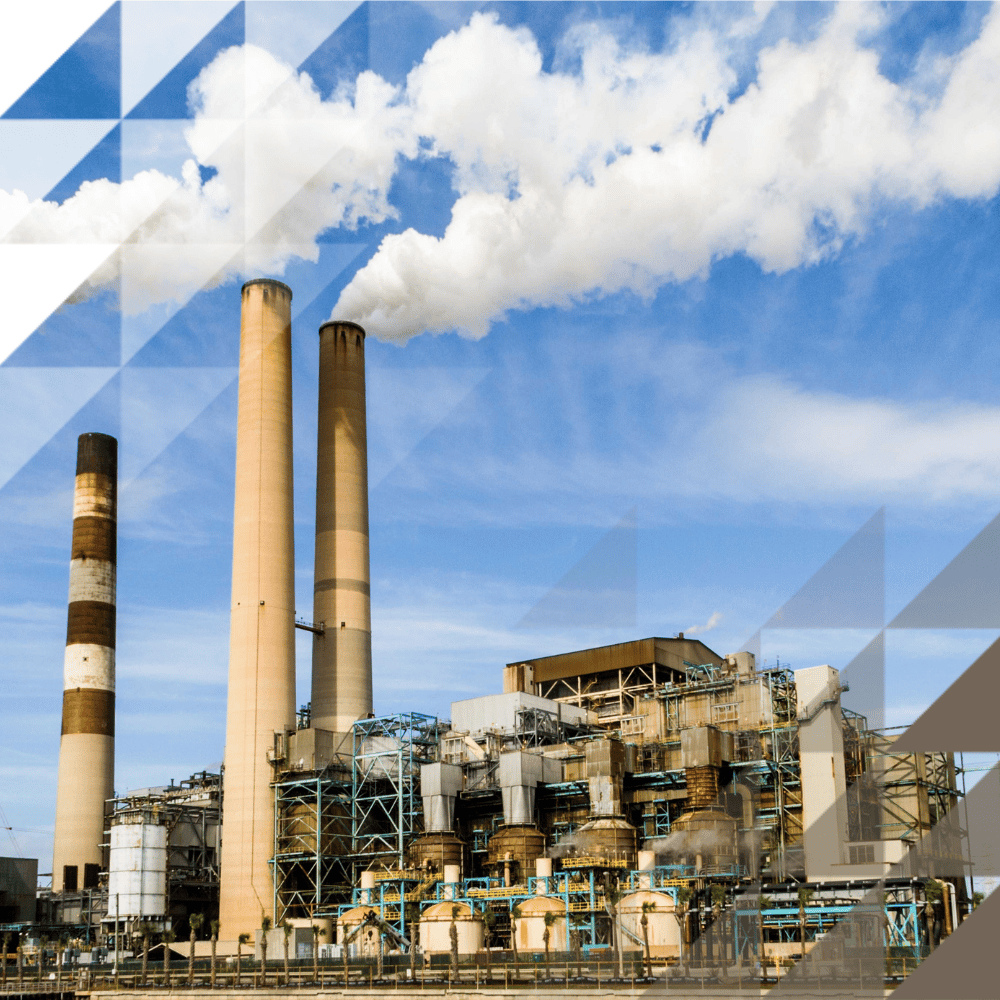 large oil and gas facilities with chimneys surrounded by pipework and smoke