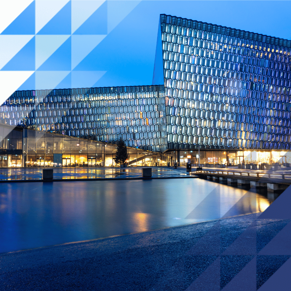 Harpa Concert Hall in Reykjavik at dusk, with its distinctive geometric glass façade illuminated and reflected in the waterfront below.