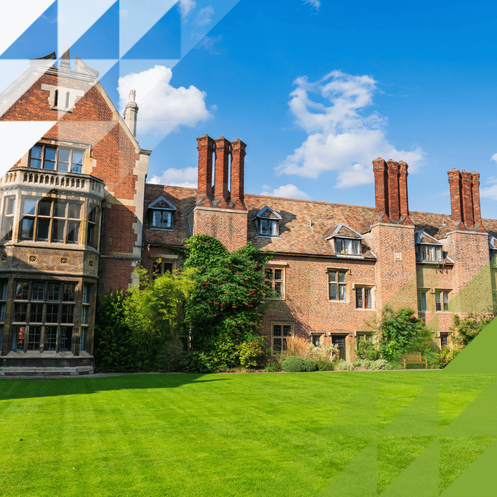 Grand Tudor red-brick building with ornate chimneys, mullioned windows and bay turret, set against manicured lawns and gardens under a blue sky.