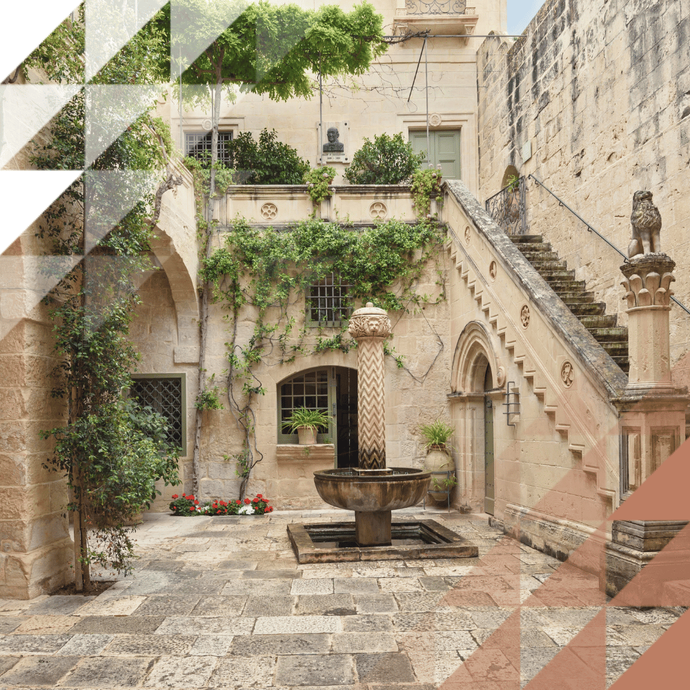 Linestone courtyard with stone fountain, climbing ivy plants, arched doorways, staircase and carved lion sculpture