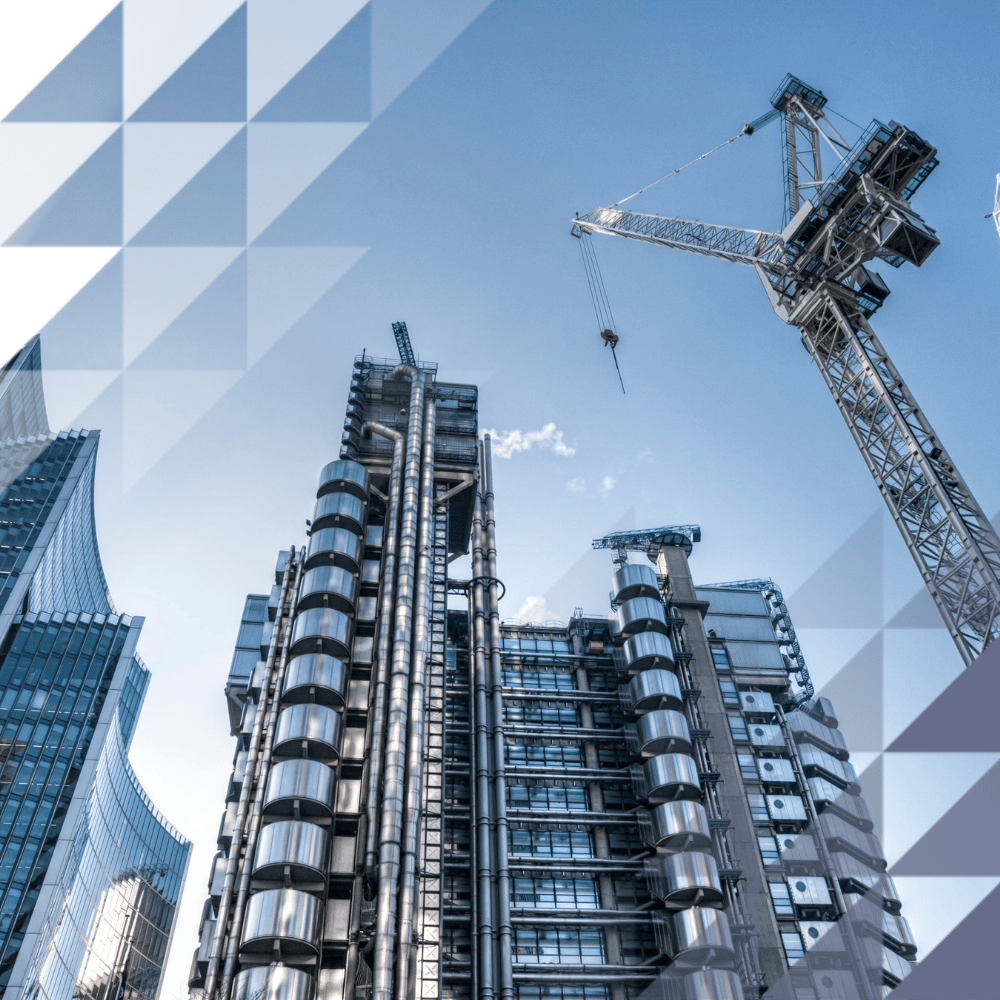 Low-angle view of modern glass and steel city skyscrapers with construction cranes