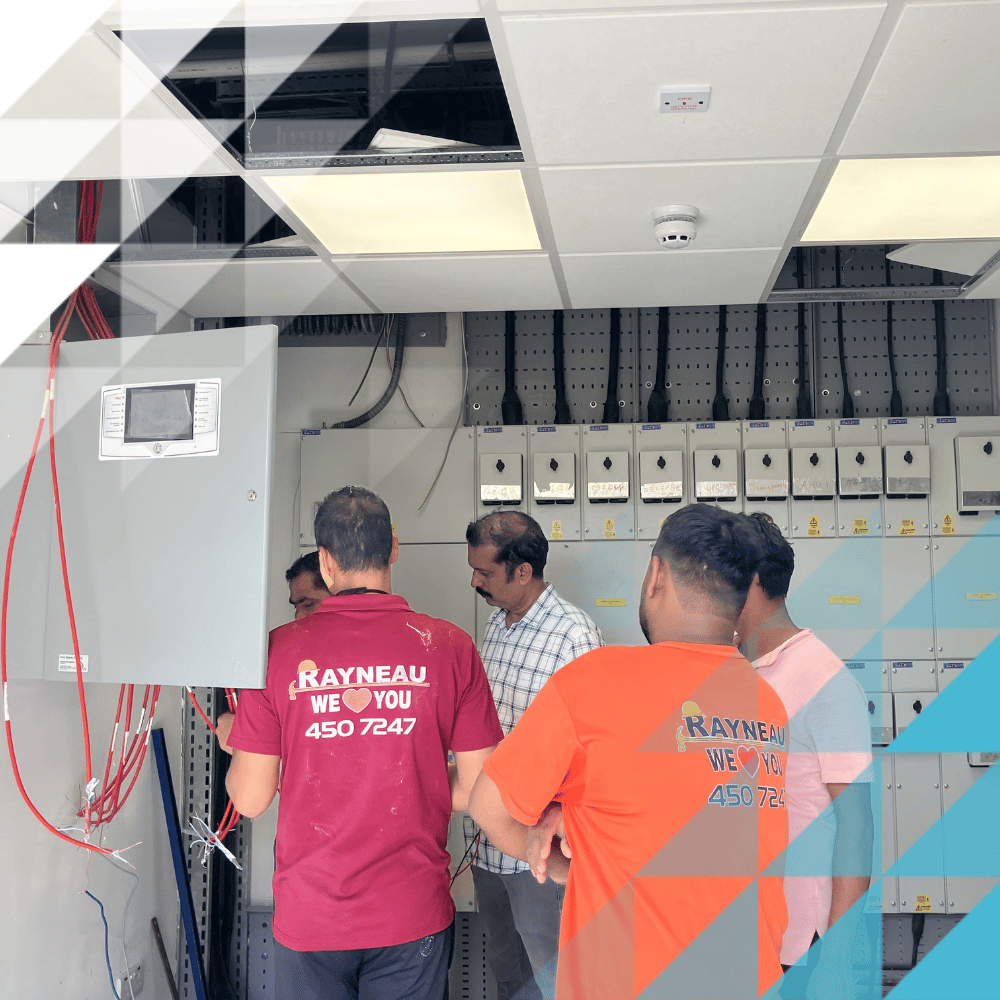 Multiple men standing around a fire panel with company t-shirts branded