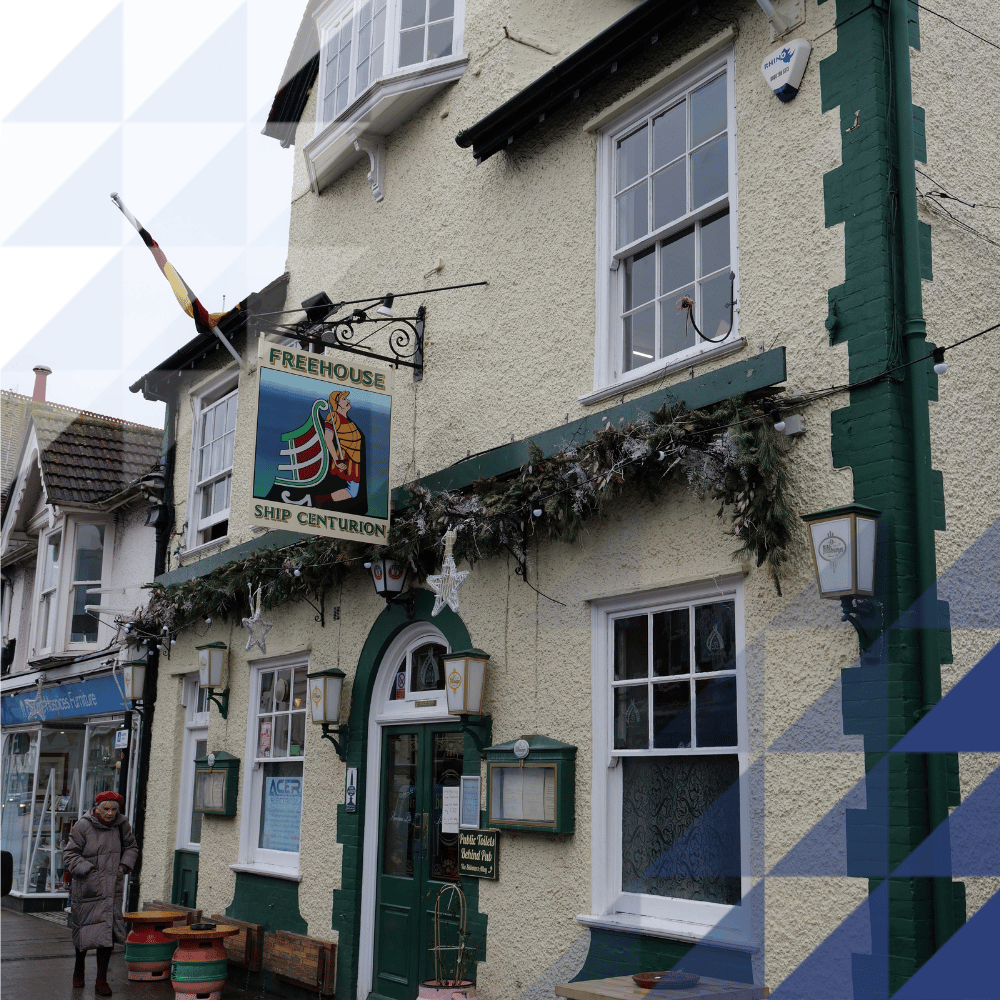 Exterior of the Ship Centurion freehouse pub — cream rendered walls, dark green trim, festive garland, on a quiet high street.