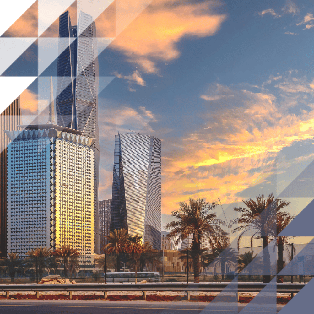 Riyadh's modern skyline at sunset, with striking contemporary skyscrapers and palm trees set against a dramatic golden sky.