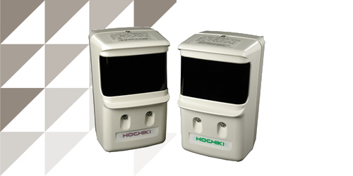 Two Hochiki optical beam smoke detectors in cream, with dark sensor windows and mounting terminals, against a grey background.