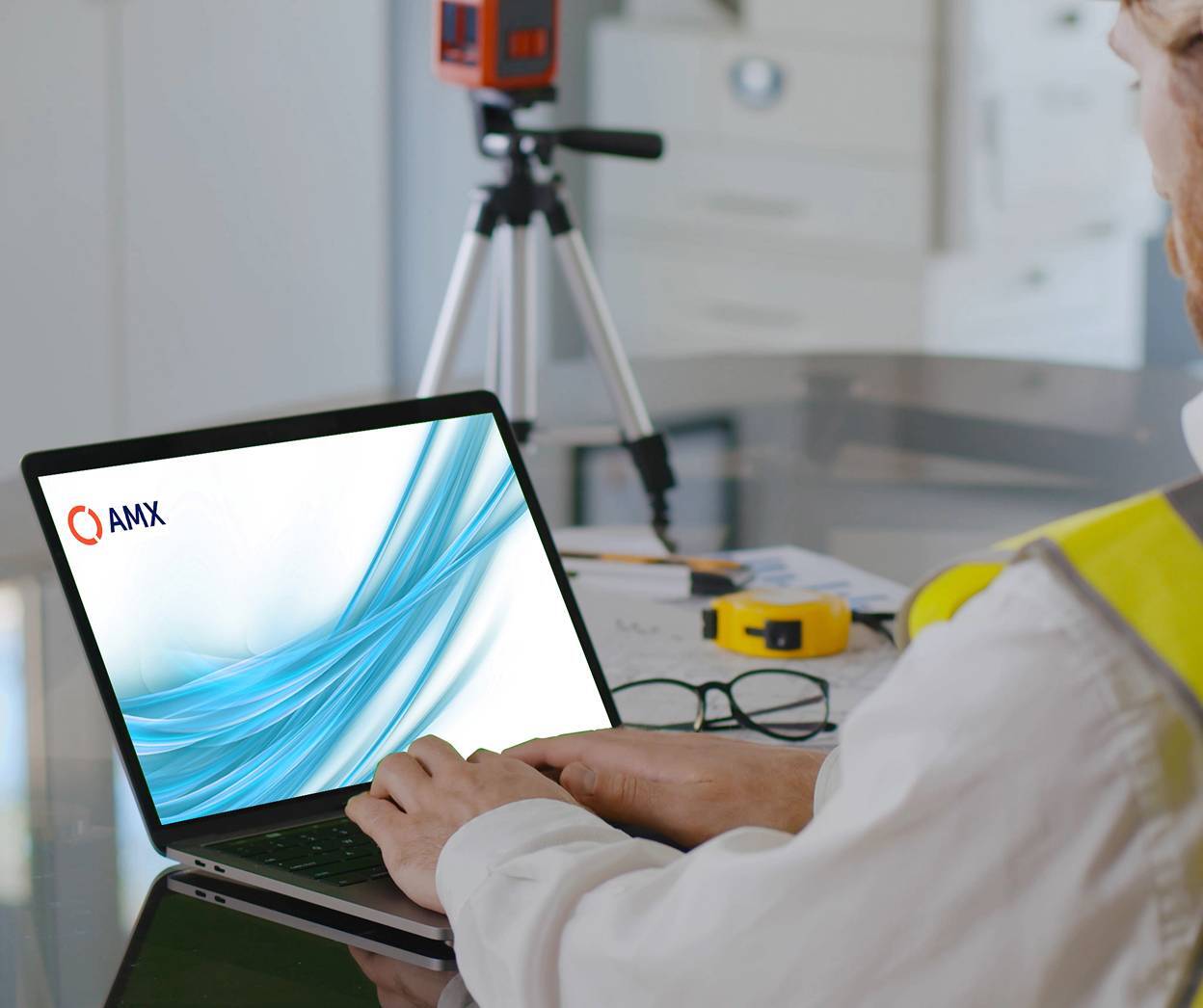 Man in hi-vis jacket using AMX software on laptop