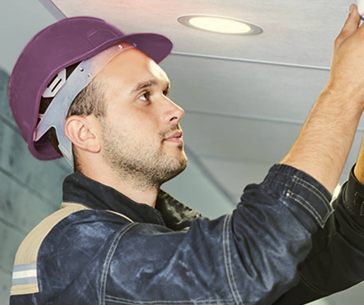 man in purple hard hat doing maintenance
