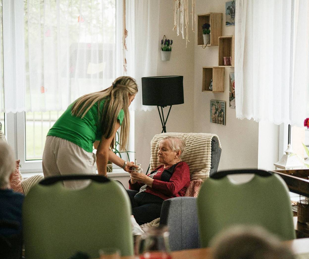 carer giving elderly woman tea