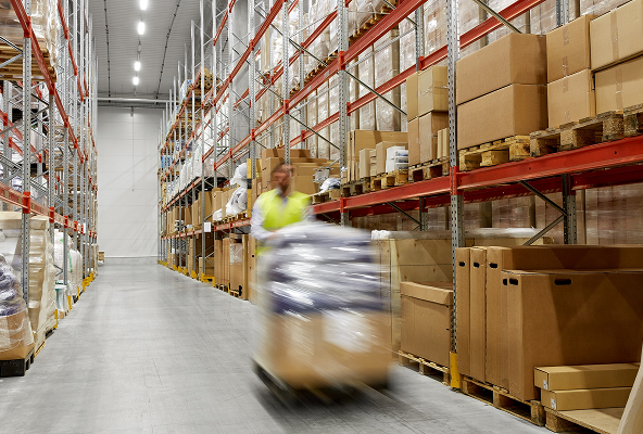 Man in hi-vis jacket walking in warehouse with motion blur